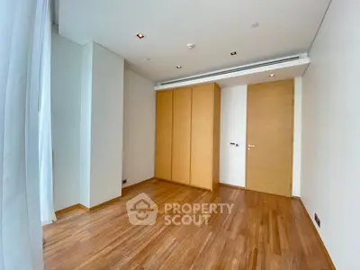 Spacious empty bedroom with wooden flooring and built-in wardrobe