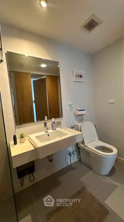 Modern bathroom with sleek fixtures and contemporary design, featuring a spacious sink and elegant lighting.