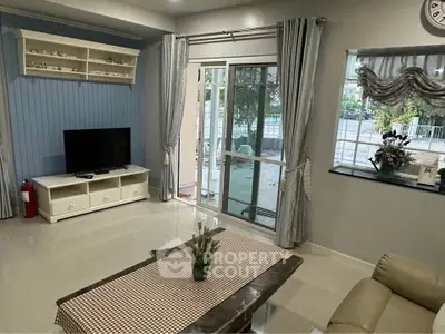 Charming living room with modern decor and garden view, featuring a cozy seating area and large windows.