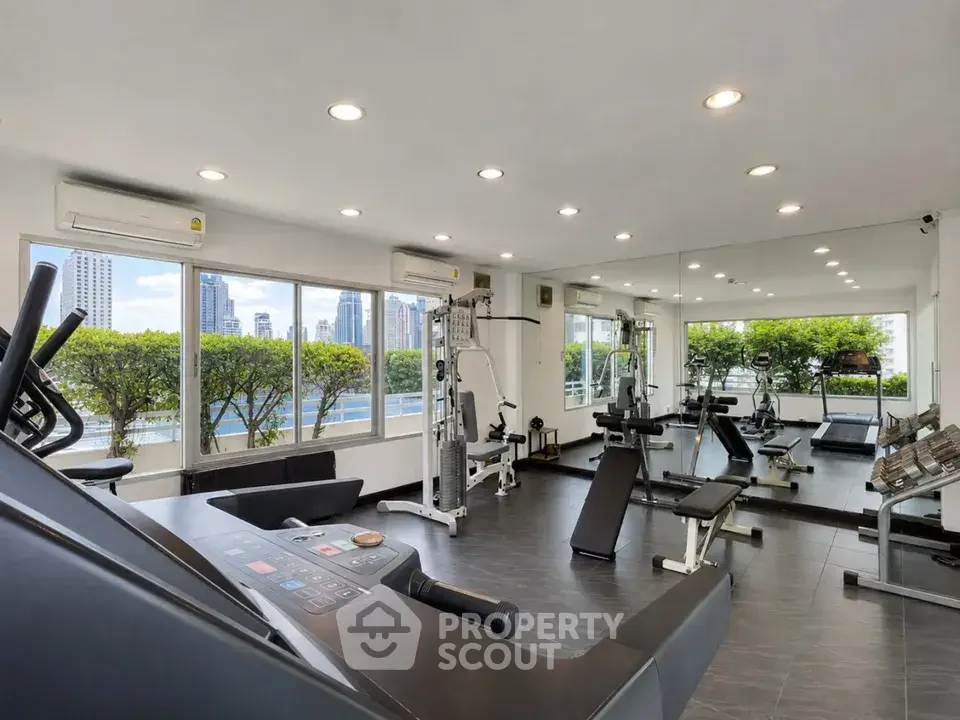 Modern gym with city view and state-of-the-art fitness equipment in a high-rise building.