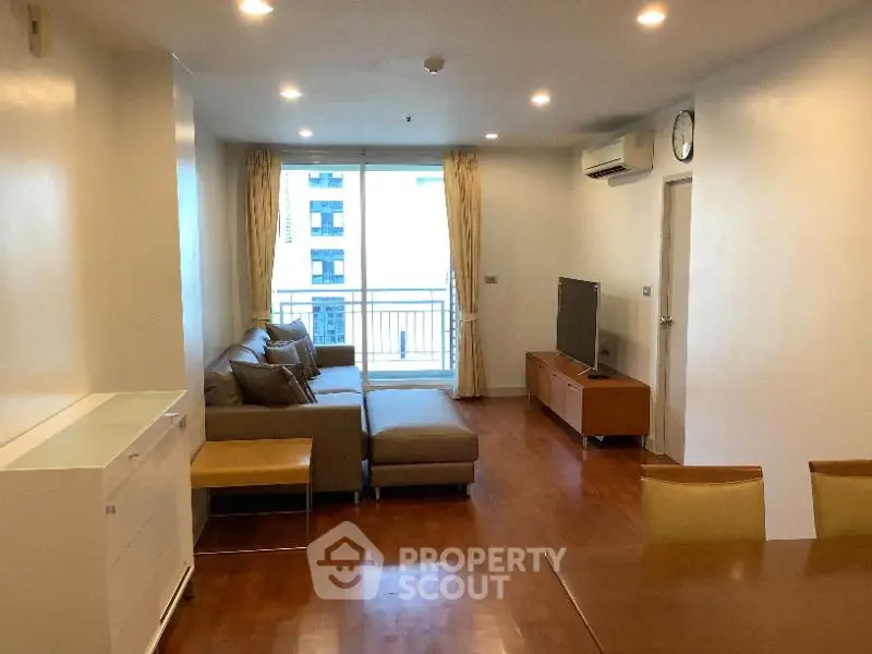 Spacious living room with modern furniture and balcony view in a high-rise apartment.