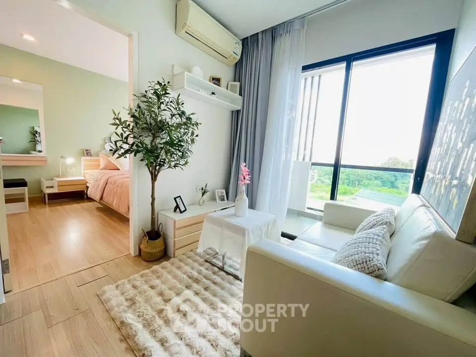 Chic modern living room with cozy decor and natural light, adjacent to a stylish bedroom.
