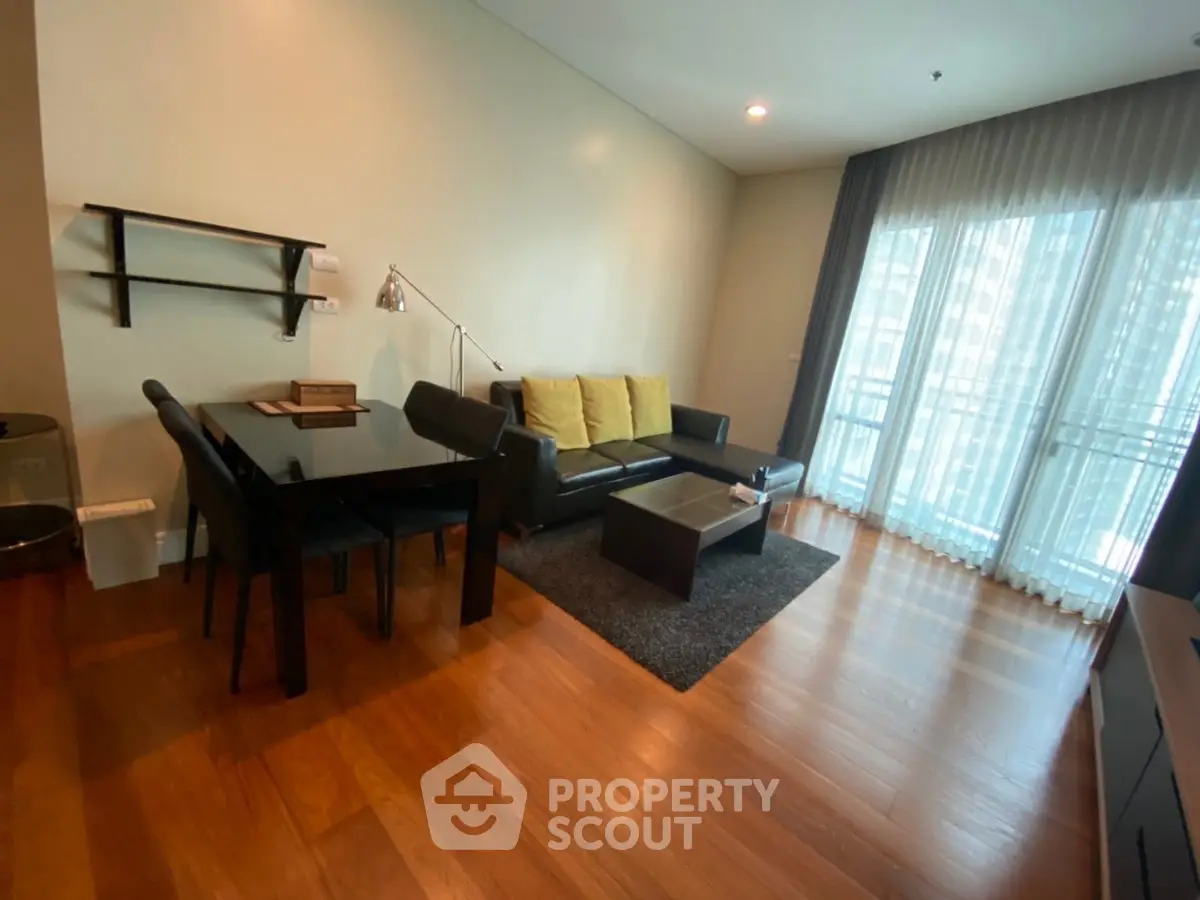 Modern living room with wooden flooring, stylish furniture, and large windows for natural light.
