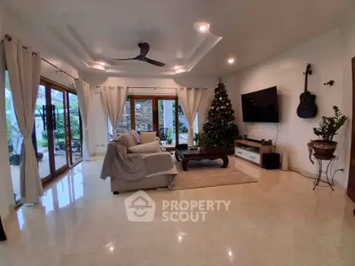 Spacious living room with modern decor, large windows, and a cozy Christmas tree, perfect for family gatherings.