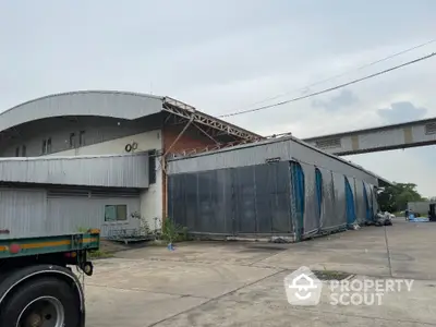 Industrial warehouse exterior with large loading area and metal roofing