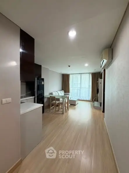 Spacious modern living room with open layout and natural light, featuring sleek furniture and wooden flooring.