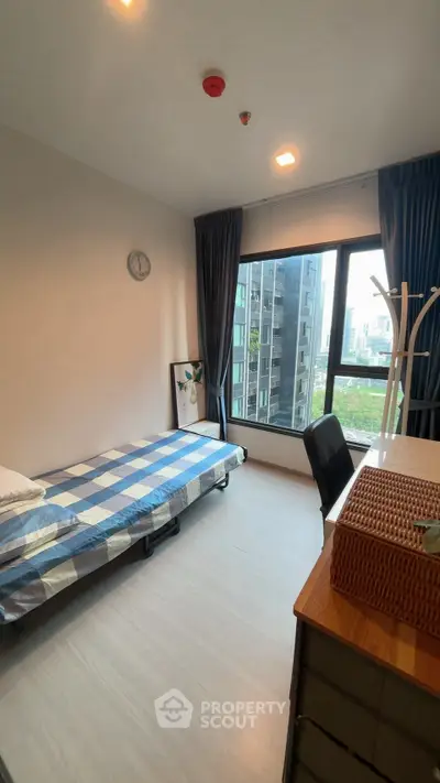 Modern bedroom with large window and city view, featuring a single bed and stylish decor.