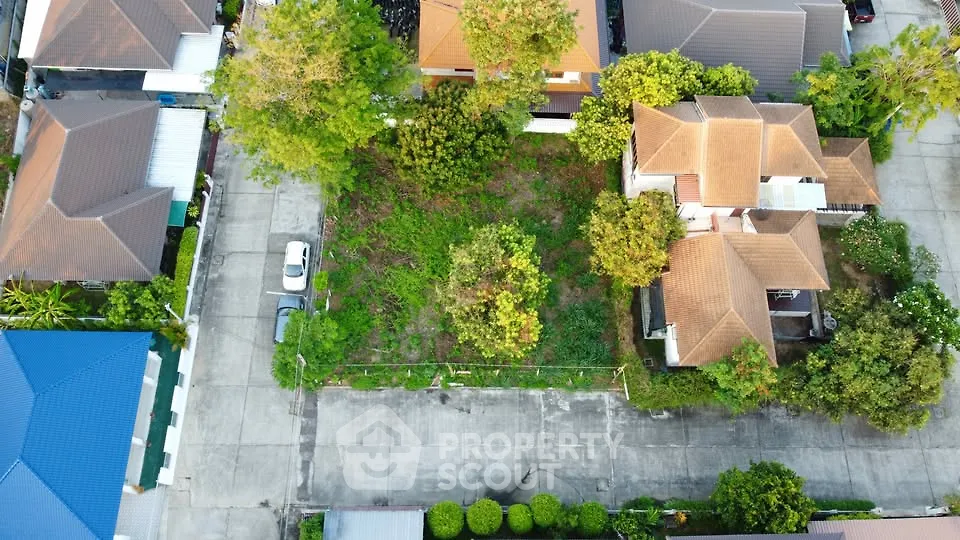 Aerial view of residential neighborhood with houses and empty plot for development.