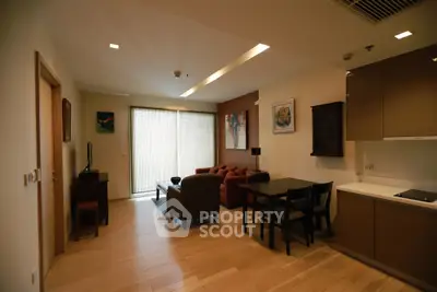 Modern living room with open kitchen, wooden flooring, and stylish decor in a cozy apartment.