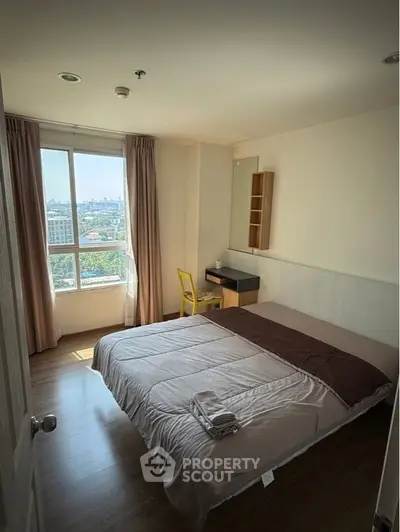 Cozy bedroom with large window offering stunning city view and natural light.