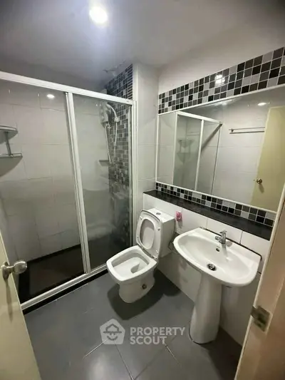 Modern bathroom with glass shower, sleek fixtures, and stylish tile accents.