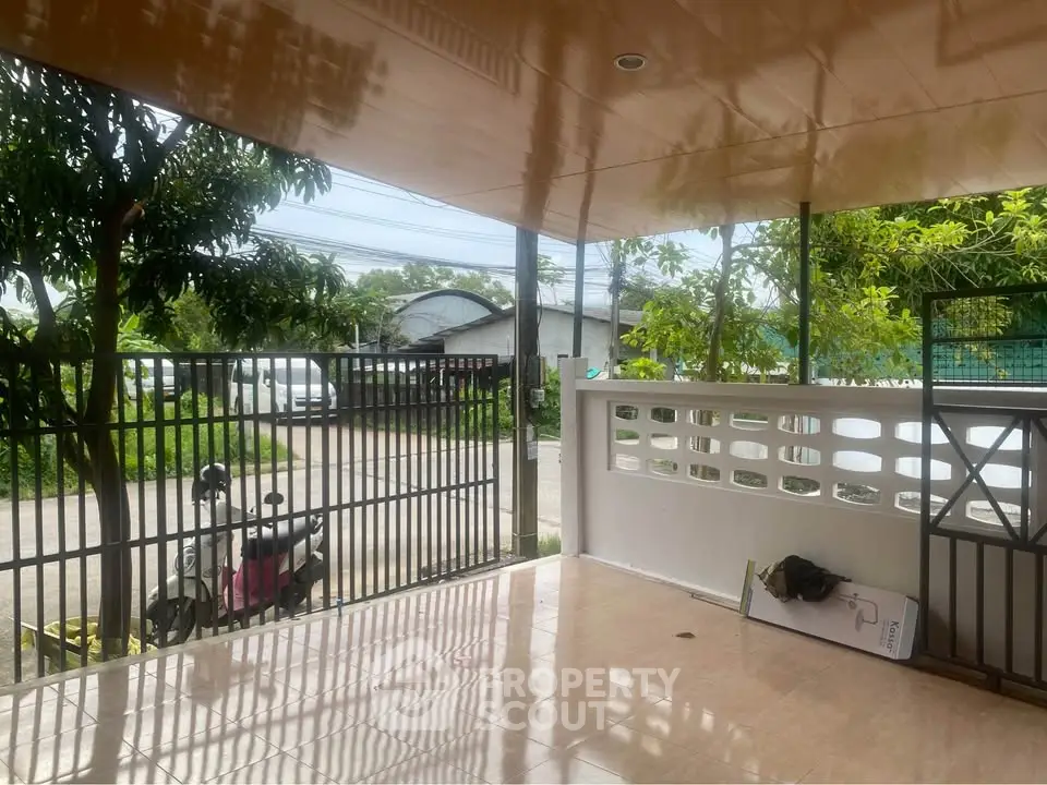 Spacious covered patio with tiled flooring and garden view, perfect for outdoor relaxation.