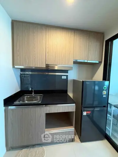 Modern compact kitchen with sleek cabinetry and stainless steel appliances in a contemporary apartment.