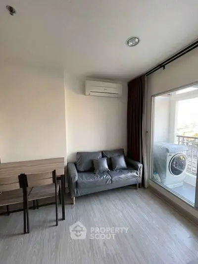 Modern living room with balcony and washing machine, featuring sleek furniture and air conditioning.