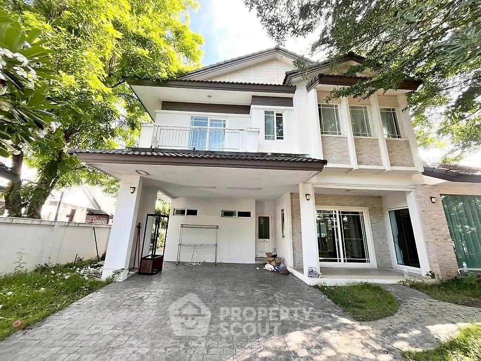 Charming two-story house with spacious driveway and lush greenery, perfect for family living.