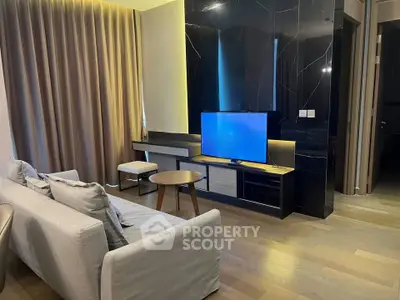 Modern living room with sleek design, featuring a flat-screen TV, stylish furniture, and elegant lighting.