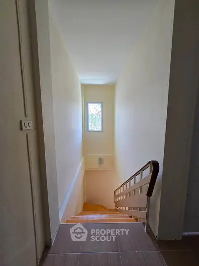 Bright stairway with natural light from window, showcasing clean and simple design in modern home.