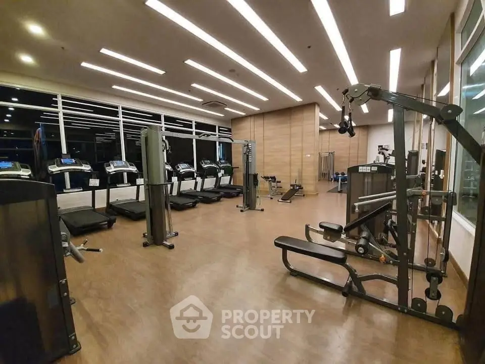 Spacious modern gym with state-of-the-art equipment and sleek wooden flooring.