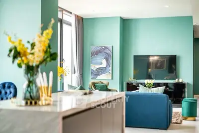 Stylish modern living room with teal walls, elegant decor, and large TV setup.