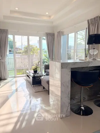 Bright modern living room with marble bar and large windows opening to garden view.