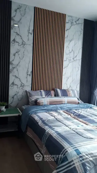 Modern bedroom with stylish marble accent wall and cozy bedding