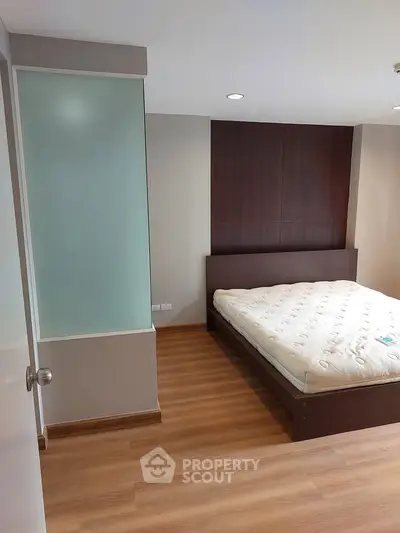 Spacious bedroom with modern design and wooden flooring, featuring a comfortable bed and stylish decor.