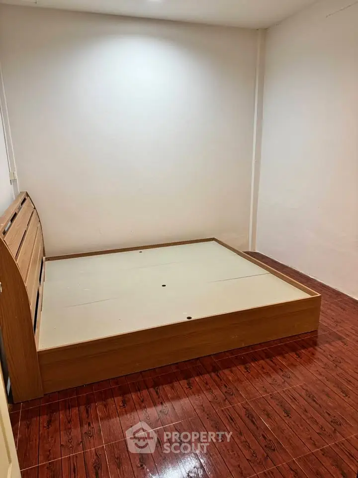 Spacious bedroom with wooden flooring and modern bed frame, ideal for cozy living.