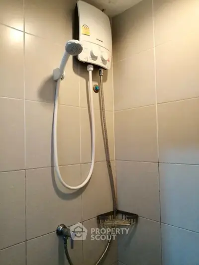 Compact bathroom shower area with modern water heater installation.