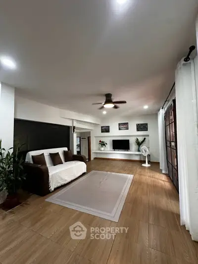 Spacious living room with modern decor and ceiling fan, perfect for relaxation.