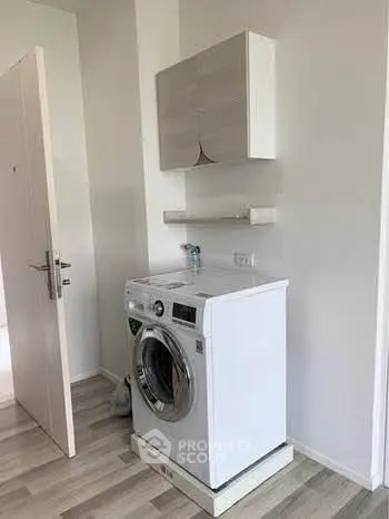Modern laundry area with washing machine and storage cabinet in sleek apartment.