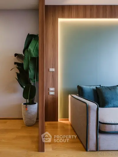 Modern living room with stylish sofa and indoor plant, featuring elegant wooden accents and soft lighting.