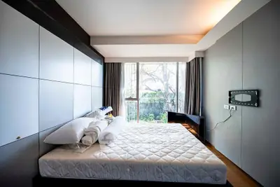 Modern bedroom with large window and minimalist design, offering a serene view of greenery.