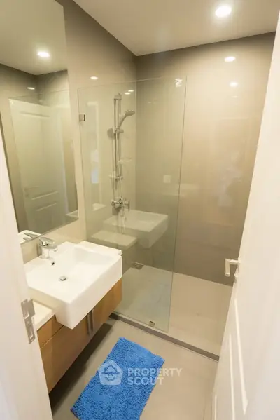 Modern bathroom with glass shower and sleek vanity in contemporary apartment.