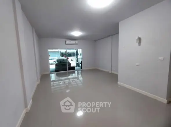 Spacious empty room with glossy floors and large window, ideal for customization.