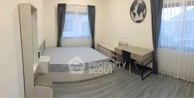 Spacious bedroom with modern furniture and large windows for natural light.