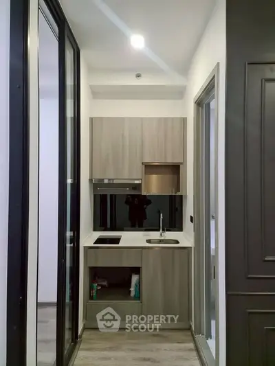Compact modern kitchen with sleek cabinetry and built-in appliances in a cozy apartment.