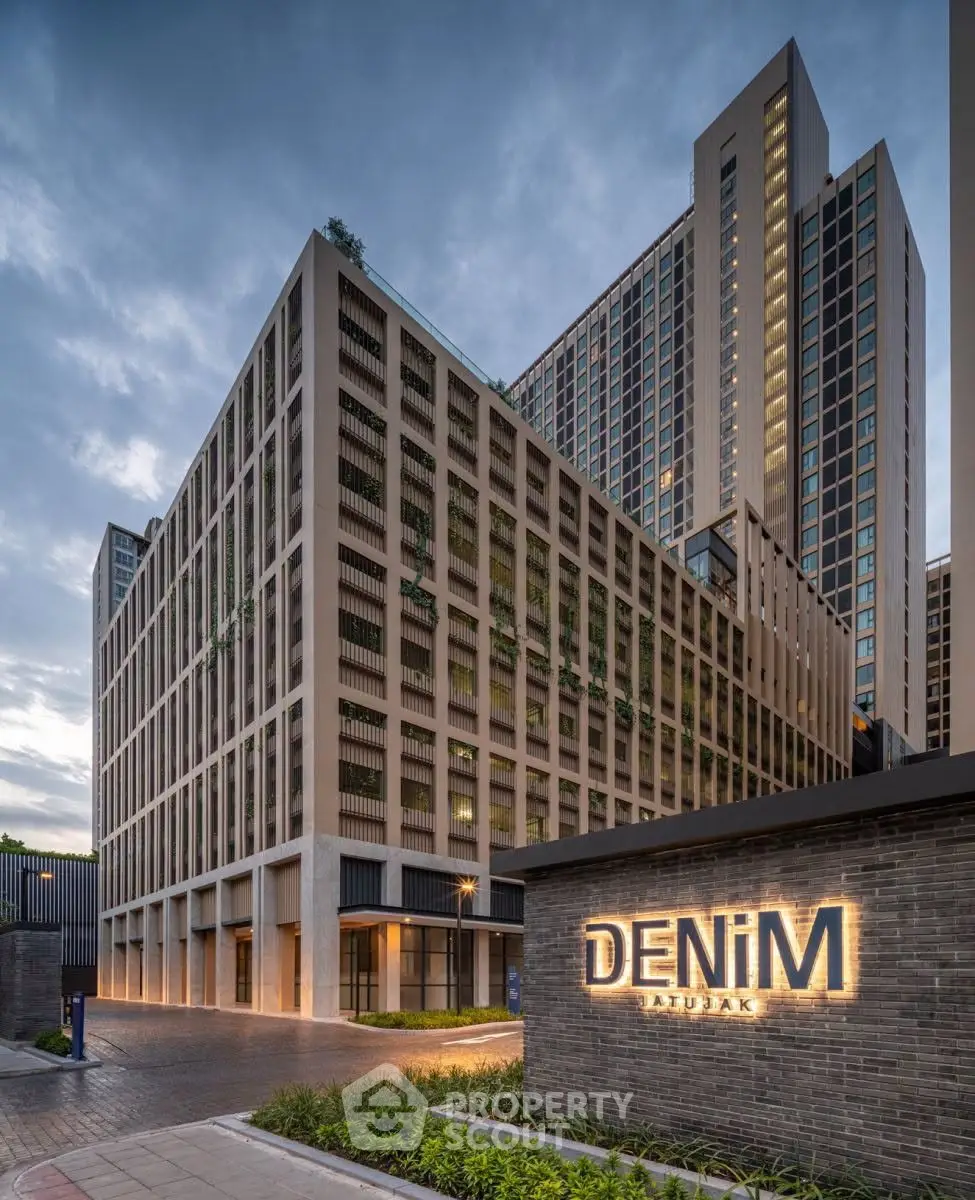 Modern high-rise building with sleek design and illuminated signage at dusk.