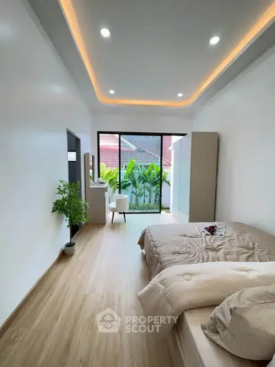 Spacious bedroom with modern decor and balcony access, featuring elegant lighting and a serene view.