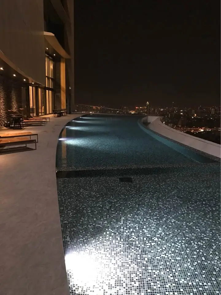 Luxurious rooftop infinity pool with stunning city skyline view at night