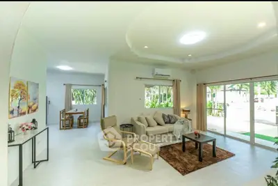 Spacious living room with modern decor and large windows offering garden views, perfect for relaxation and entertaining.
