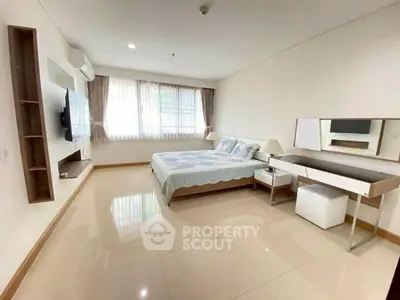 Spacious bedroom with modern decor and natural light in a stylish apartment.
