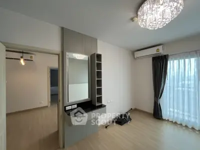 Modern bedroom with elegant chandelier and large window, featuring built-in vanity and air conditioning.