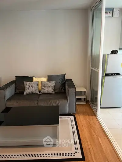 Modern living room with sleek furniture and adjacent kitchen area in a stylish apartment.
