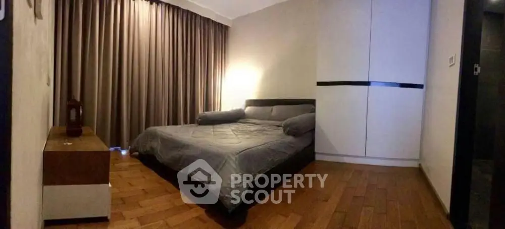 Cozy bedroom with modern decor and wooden flooring, featuring a large bed and stylish wardrobe.