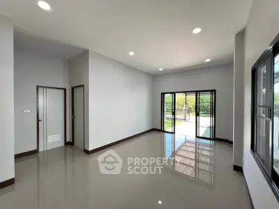 Spacious modern living room with large windows and glossy floors, offering abundant natural light and outdoor access.