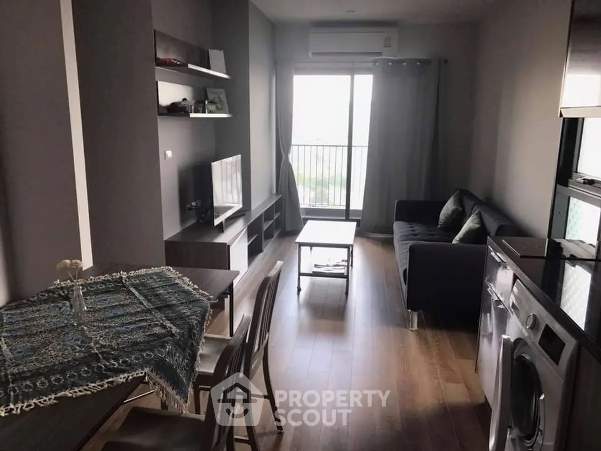Modern living room with balcony, featuring sleek furniture and appliances.