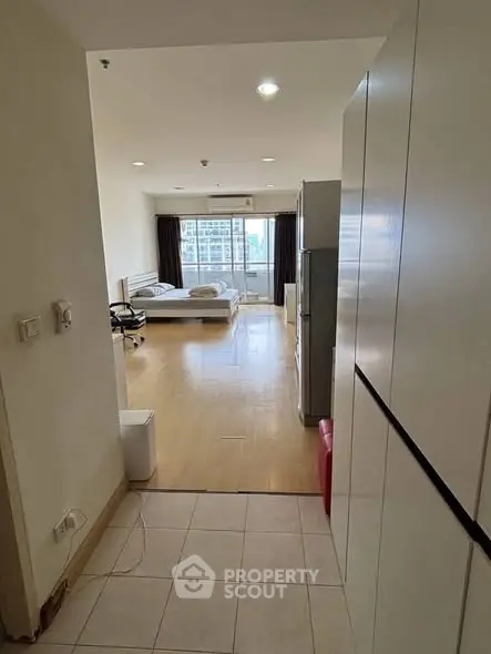 Spacious studio apartment with modern furnishings and large windows offering city views.