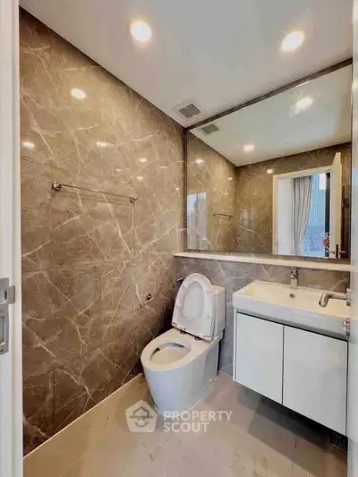 Modern bathroom with marble walls and sleek fixtures in luxury apartment.