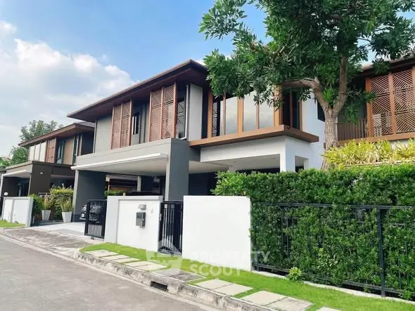 Modern two-story house with lush greenery and sleek architectural design in a serene neighborhood.