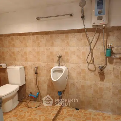 Functional bathroom with urinal, toilet, and shower in tiled setting